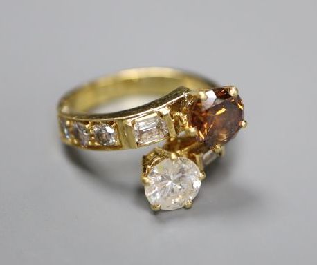 A modern yellow metal and two colour diamond two stone crossover ring,